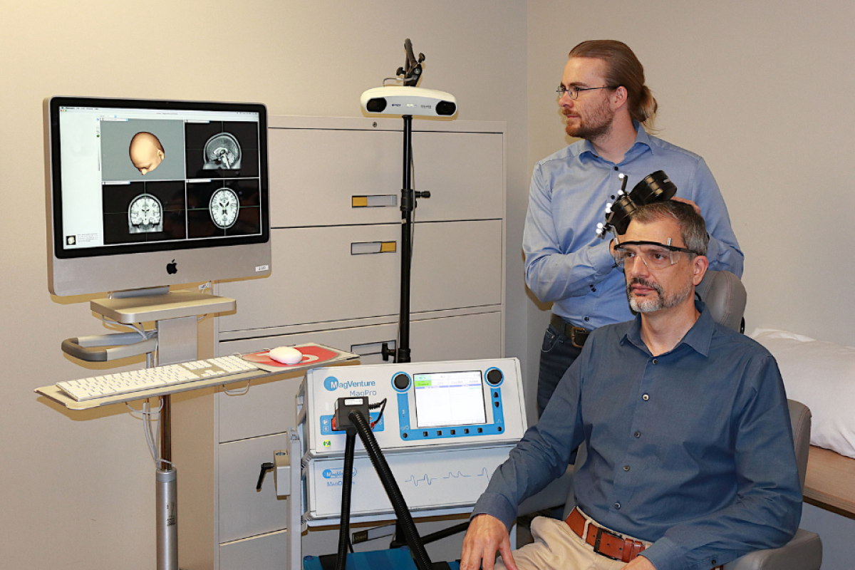 Postdoctoral associate Dr. Lari Koponen demonstrates TMS under computer navigation on Dr. Angel Peterchev in the Brain Stimulation Research Center.
