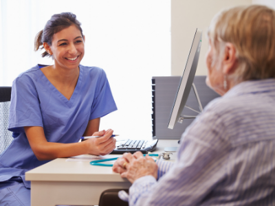 Woman in scrubs speaking to older patient