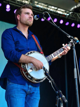 Greg Robbins-Welty playing banjo on stage