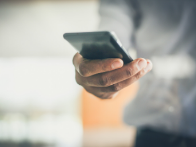 Man holding cell phone - hands only - blurred background