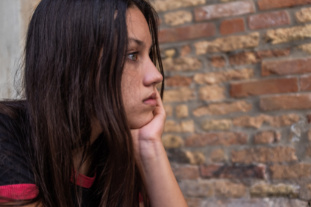 Pensive teenage girl with brick wall in background