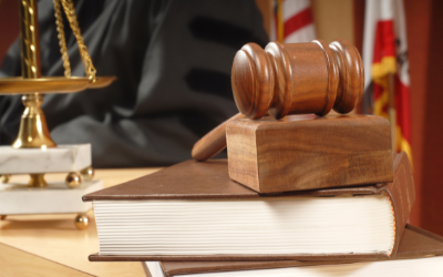 Gavel on top of stack of books with scale and judge in background