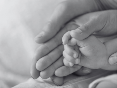 Baby's and parents' hands folded together (black and white)