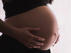 Woman with her hands on her pregnant belly - belly only