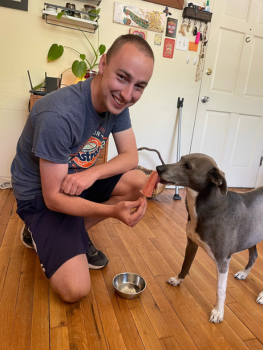 Alex treating one of their dogs (Callie, a Whippet mix) with a dog food popsicle.