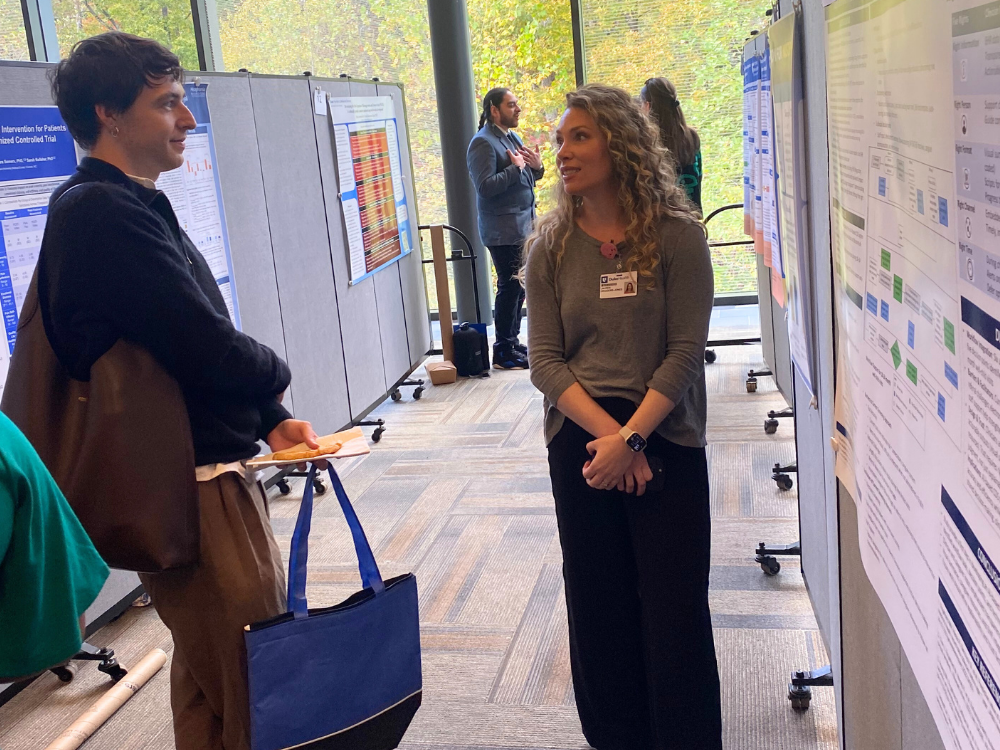 Researcher presenting her poster to a retreat attendee