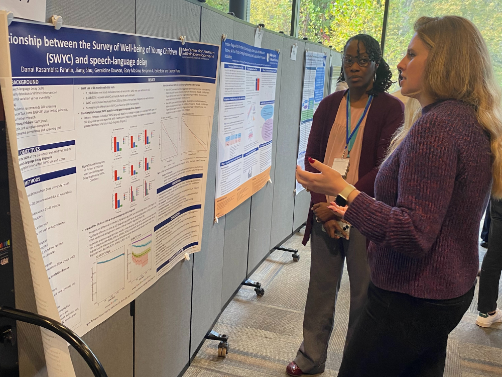 A researcher discusses her poster with a retreat attendee