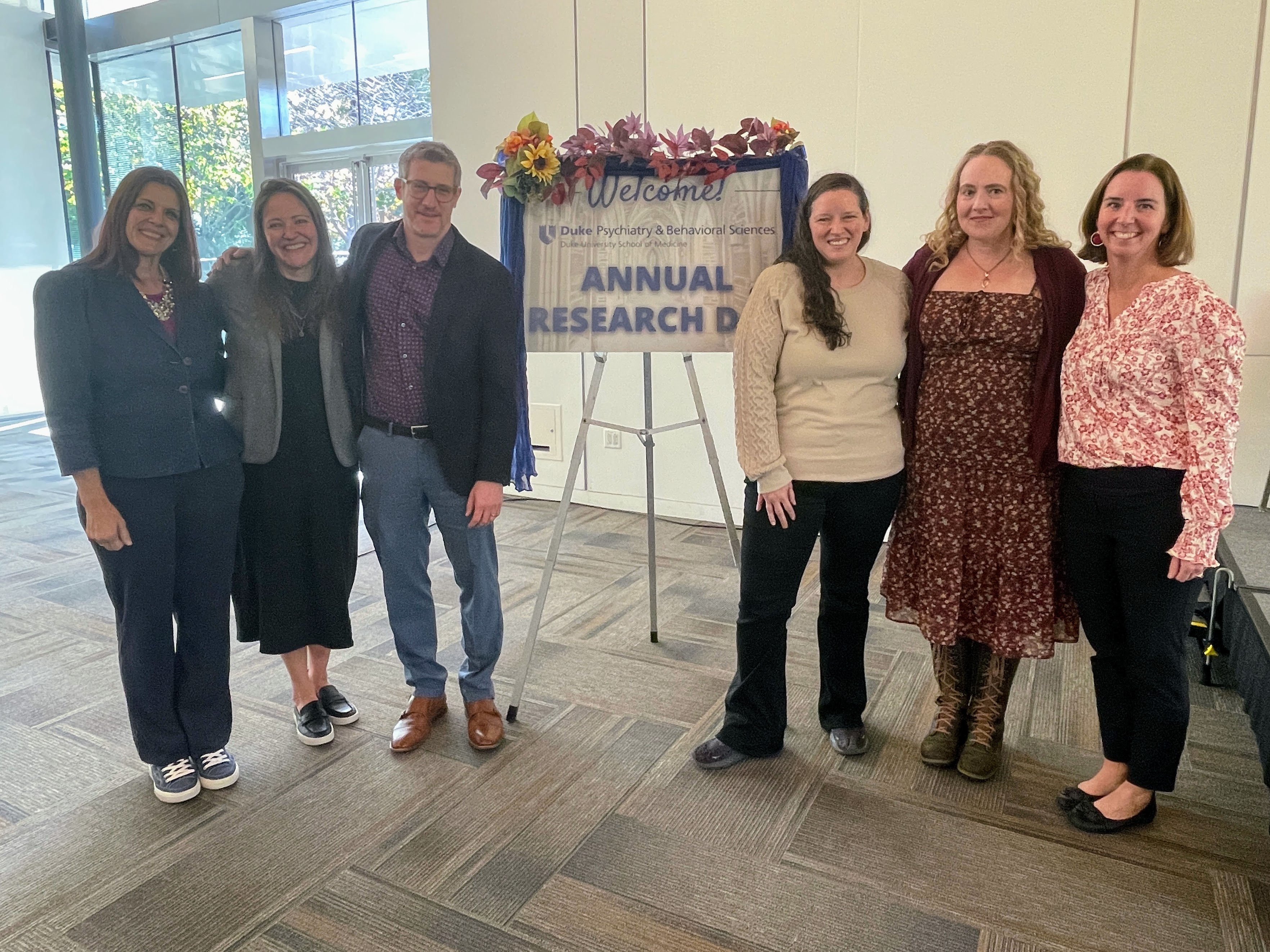 Team who organized event standing in front of Annual Research Day sign