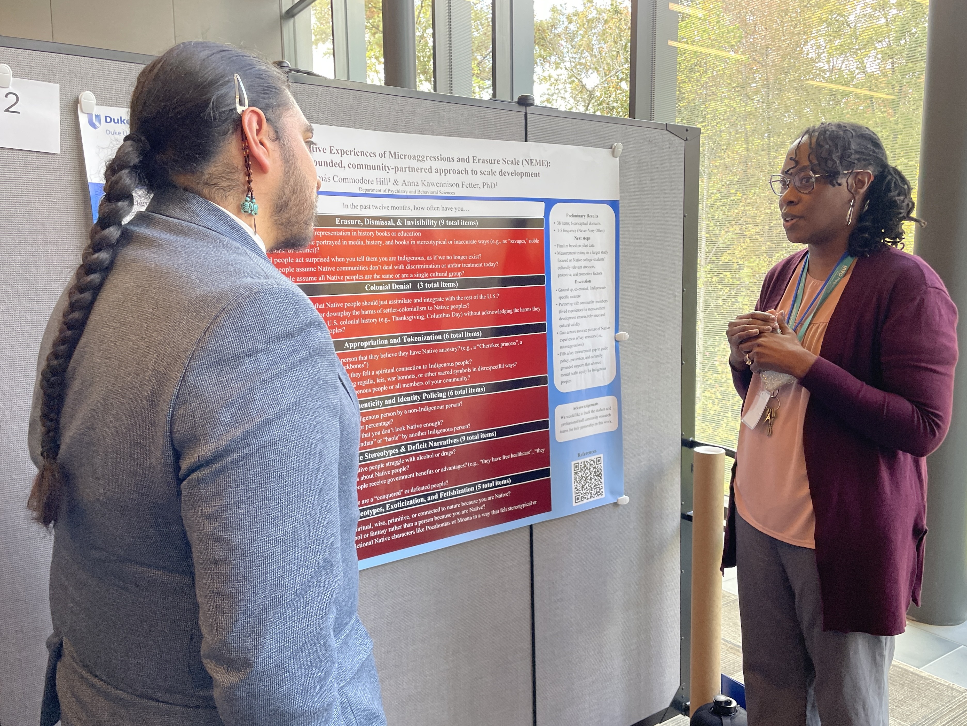 Researcher presenting poster to attendee