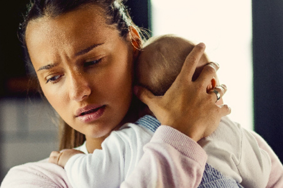 Woman holding baby and looking troubled
