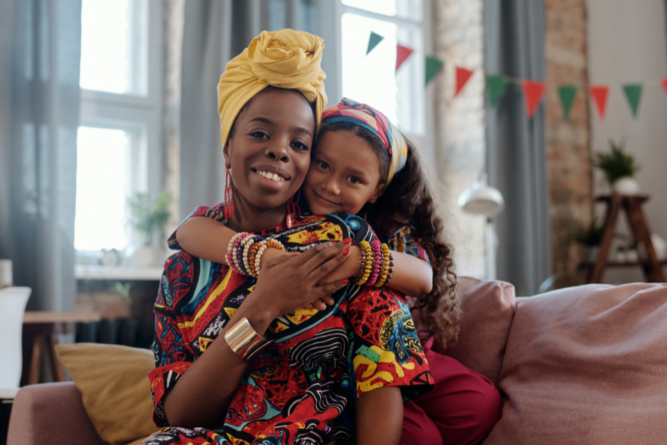 Young girl behind woman with arms around woman