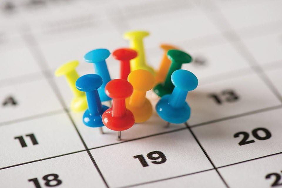 Colorful pushpins all pushed into one day on a paper calendar