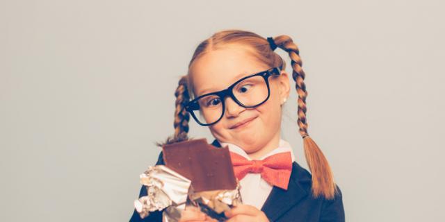 excited girl with pigtails eating a candy bar