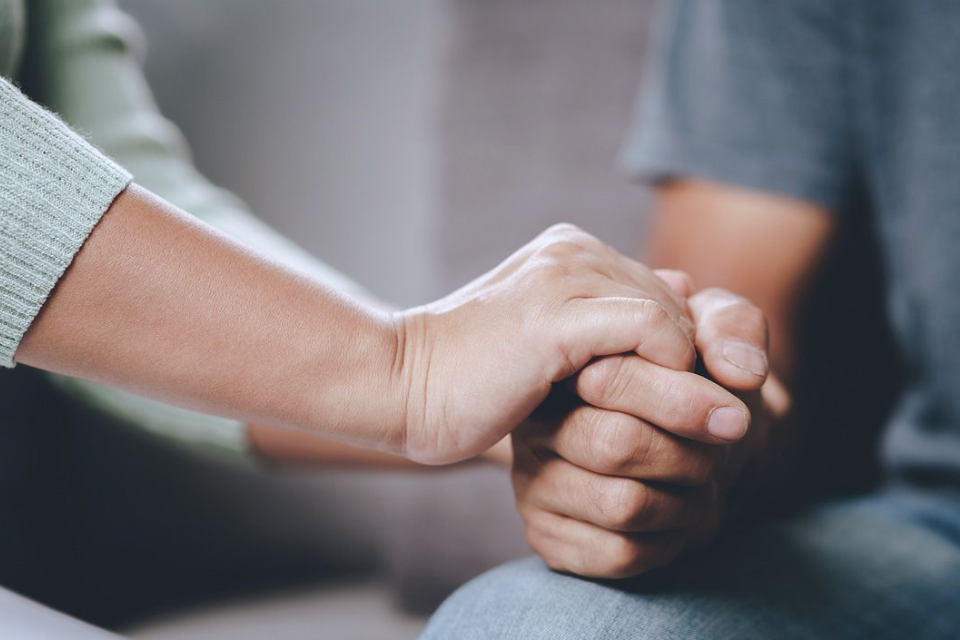Two people holding hands demonstrating support (hands and arms only)