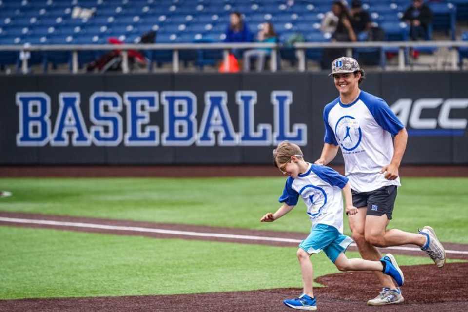 Duke Baseball player runs with Baseball Bonanza participant