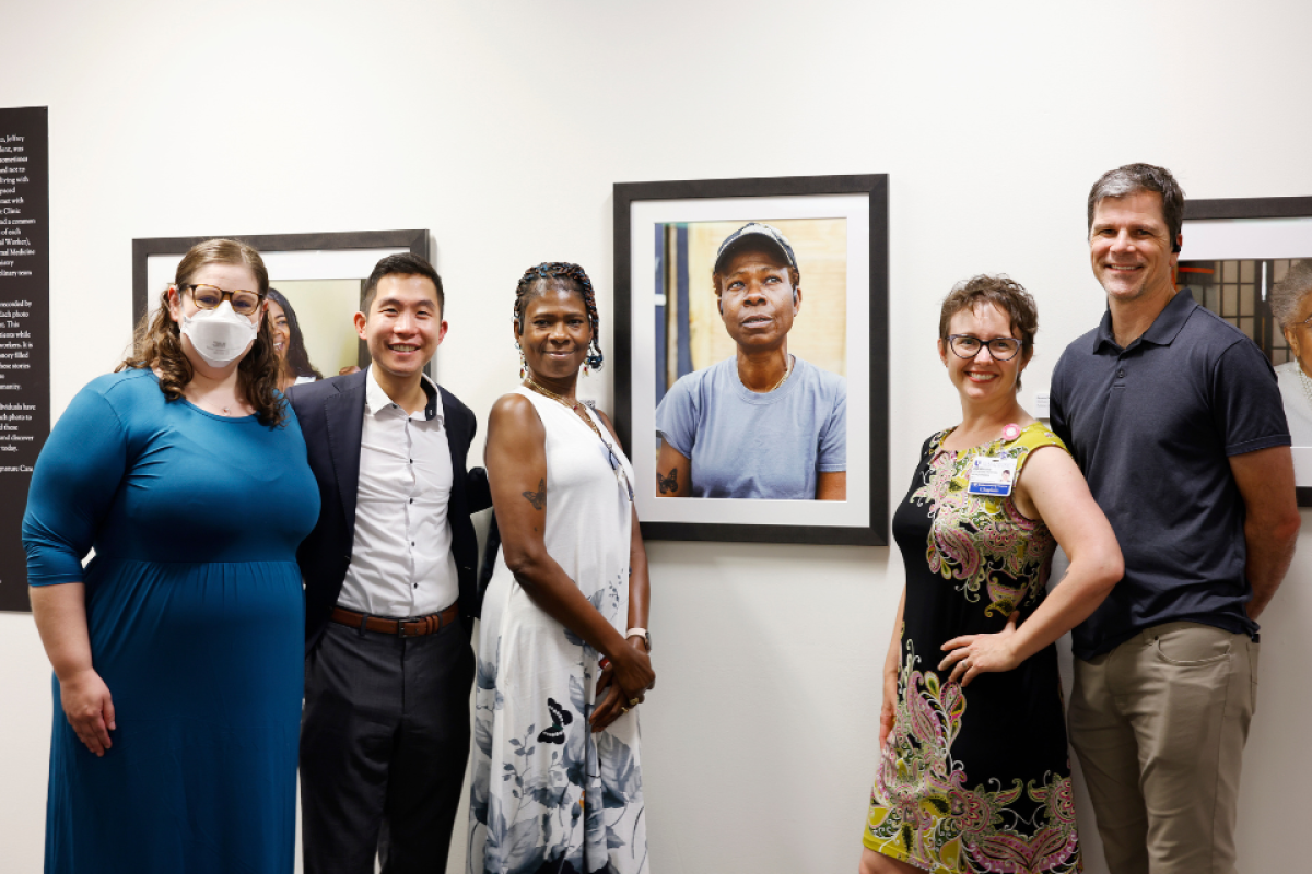 Project leaders and patient pose in front of the patient's portrait