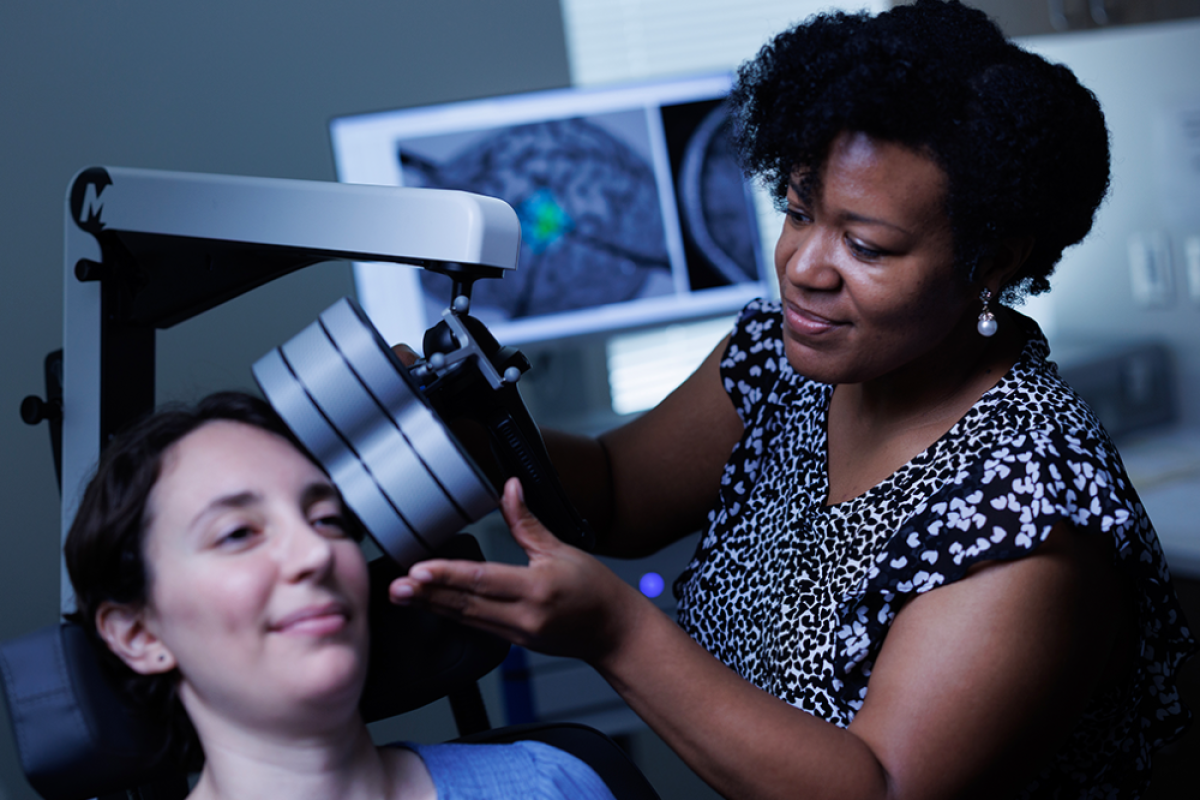 Researcher Dr. Tonisha Kearney-Ramos demonstrates repetitive transcranial magnetic stimulation on a colleague.