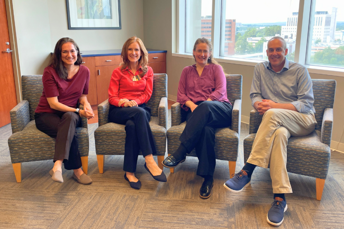 Four adults sitting in front of a window