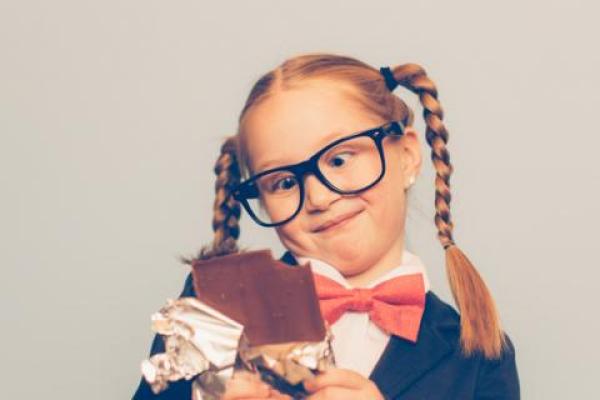 excited girl with pigtails eating a candy bar