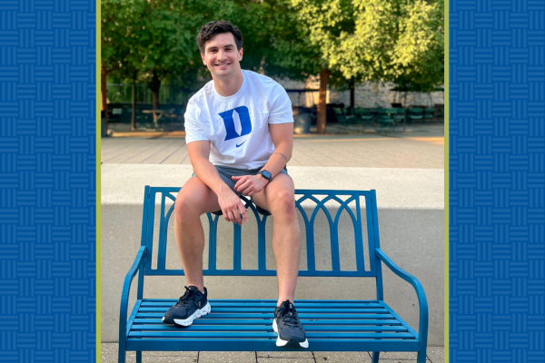 Andres Fuenmayor sitting on blue bench with Duke t-shirt