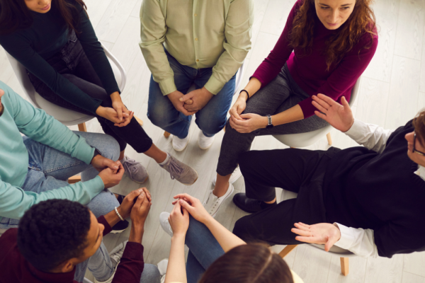 Young adults engaged in group therapy (view from above, faces not showing)