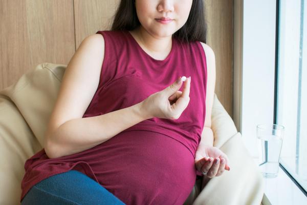 Pregnant woman holding pill
