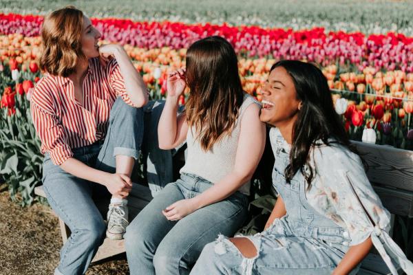 diverse women sitting and laughing outside in front of flowers