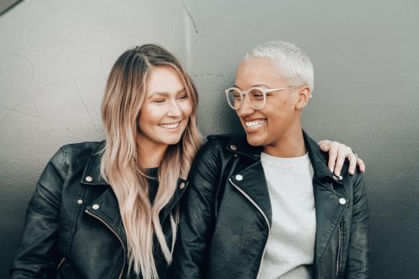 Two young adult women in leather jackets smiling