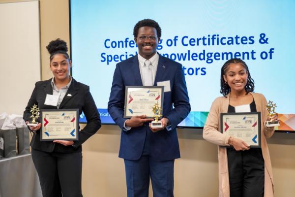 Three students holding certificates and small trophies