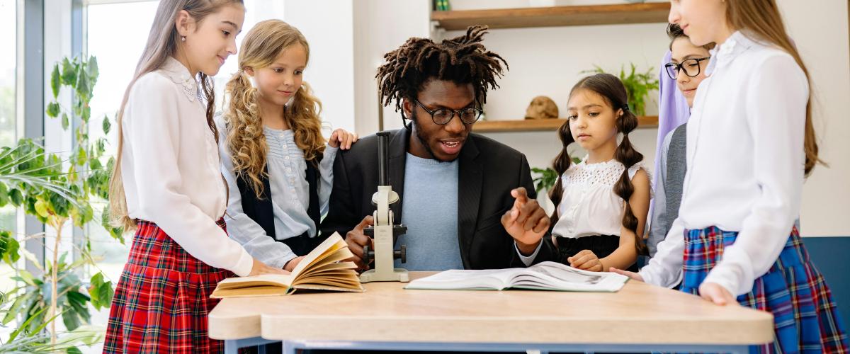 Teacher with girls and microscope