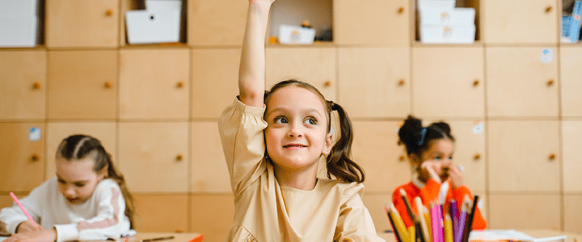 young girl raising her hand in class