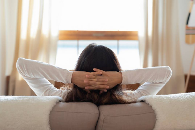 Woman sitting on couch with hands behind her head