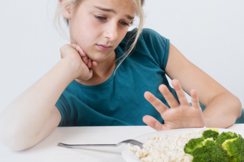 Teen girl pushing away a plate of food