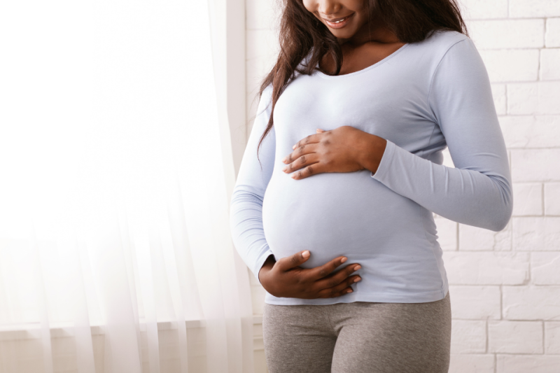 Pregnant woman looking down and holding belly