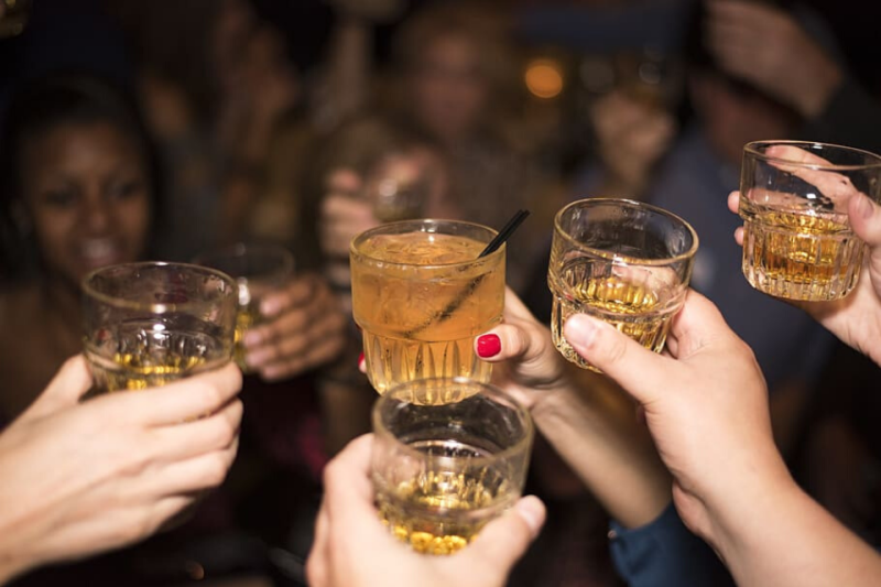 Group of people doing cheers with alcoholic drinks