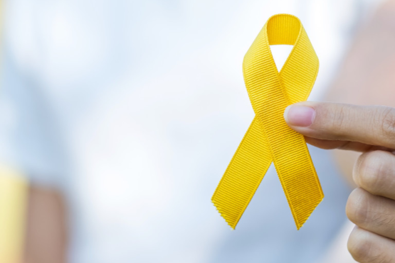 Person (hands only) holding yellow ribbon representing suicide prevention