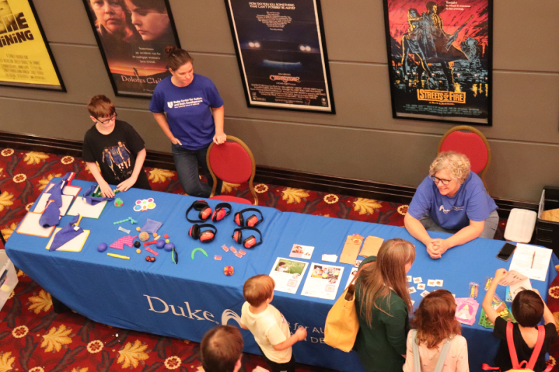 Overhead view of sensory kit table with staff from Autism Center behind table and children looking at items on table.