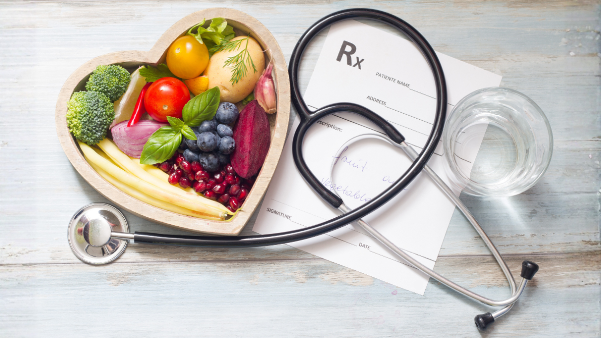 Fruit in a heart-shaped bowl. Stethoscope. Glass of water. Paper prescription.