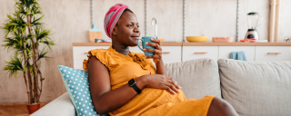Pregnant woman sitting on couch holding mug