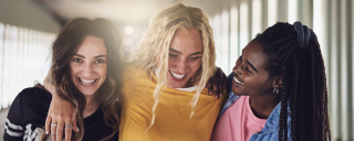 Three young women with arms around each other laughing