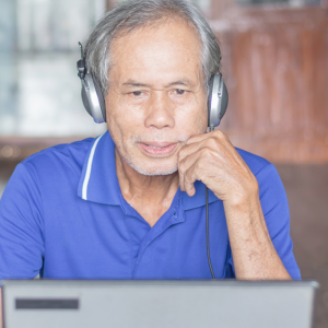 Older adult man with headphones looking at laptop