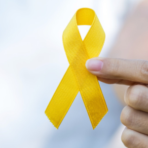 Person (hands only) holding yellow ribbon representing suicide prevention