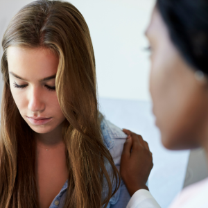 Sad teen talking with supportive clinician