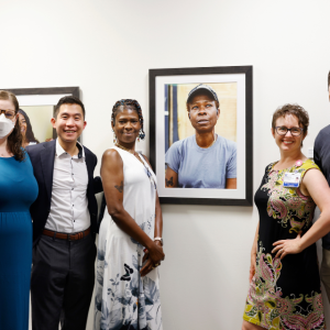 Project leaders and patient pose in front of the patient's portrait