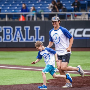 Duke Baseball player runs with Baseball Bonanza participant