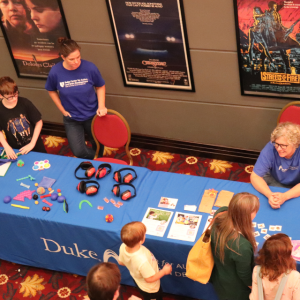 Overhead view of sensory kit table with staff from Autism Center behind table and children looking at items on table.