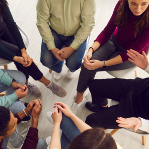 Young adults engaged in group therapy (view from above, faces not showing)
