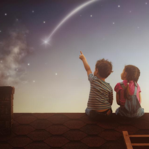 Two young children sitting on a rooftop with a shooting star falling. One child is pointing to the shooting star.