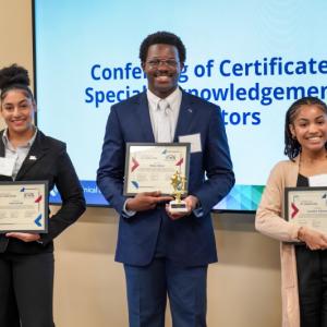 Three students holding certificates and small trophies
