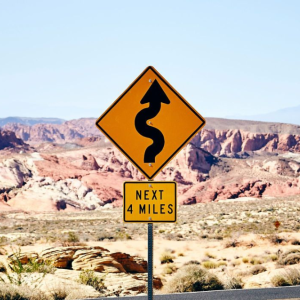Rough terrain landscape with road sign indicating curvy road for next 4 miles
